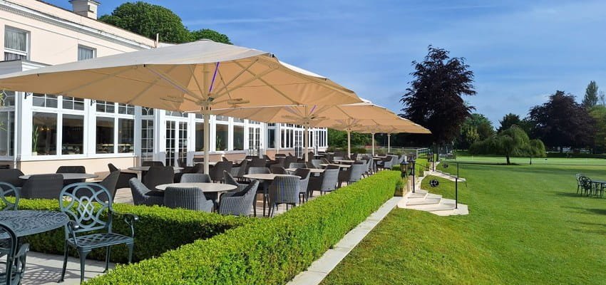Commercial umbrellas shading the terrace dining area at Phyllis Court Members Club, Henley-on-Thames